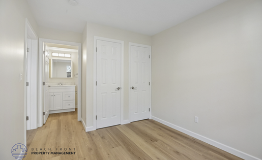 A white bedroom with a dresser and a mirror.